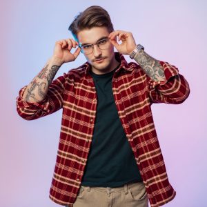 Studio portrait of a hipster man in fashionable clothes wears glasses in a studio with creative lighting