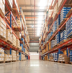 Rows of shelves with goods boxes in huge distribution warehouse at industrial storage factory.