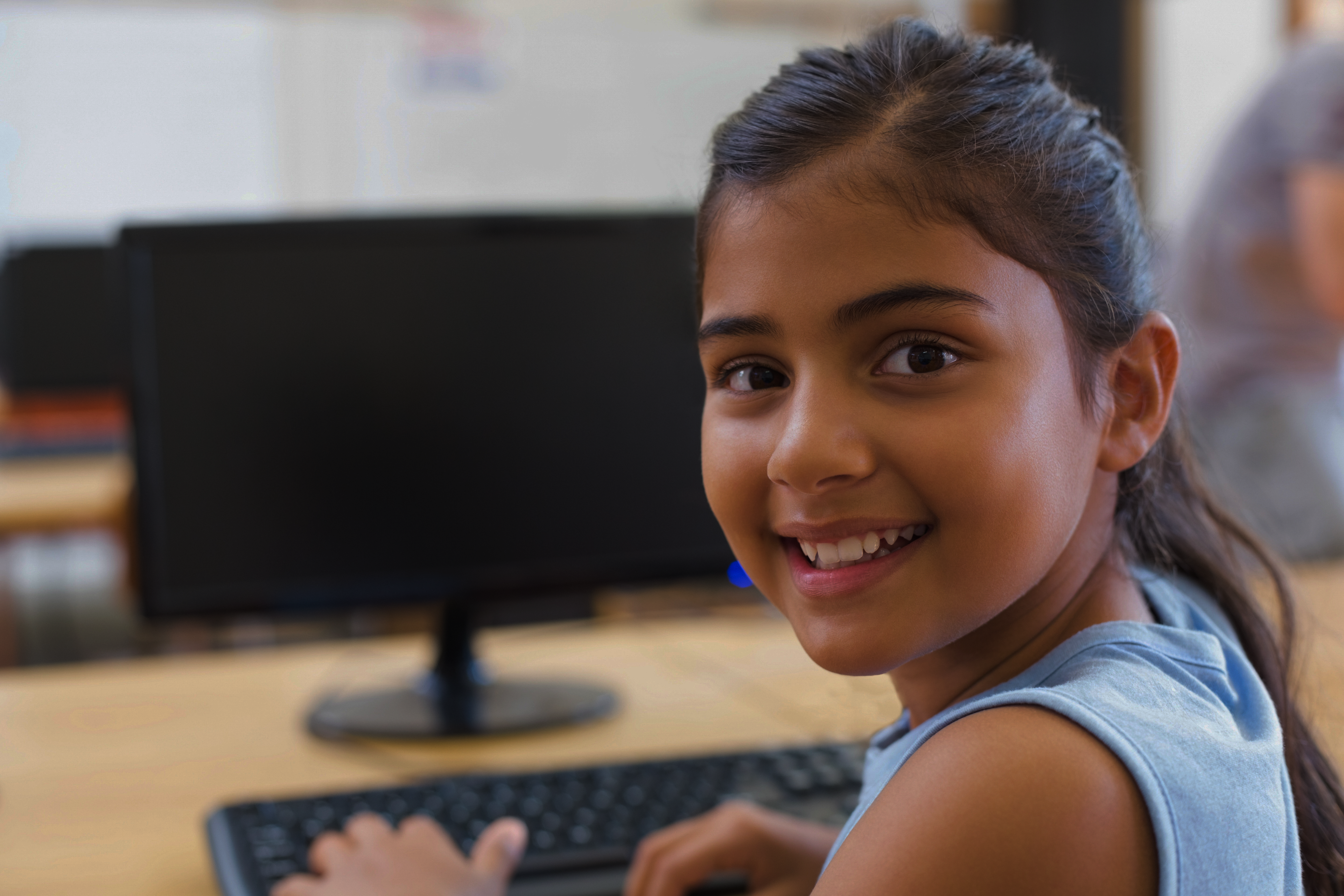Girl Smiling with Computer in Background